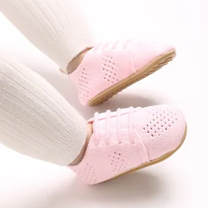Close-up of pink knitted baby shoes with hollow design and lace-up detail.