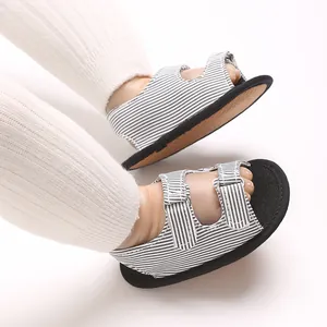 Close-up van zwart-wit gestreepte baby-sandalen met verstelbare bandjes en zachte zolen.