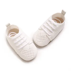 Close-up detail of white knitted baby shoes featuring a decorative hollow heart pattern