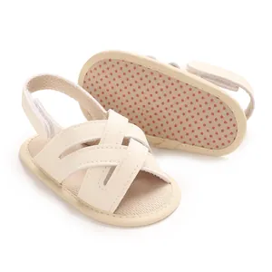 Detalle de sandalias de bebé en PU crema con suela blanda antideslizante de puntos y correas.