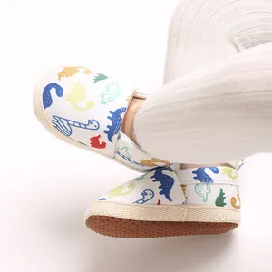 Primer plano de zapatos clásicos para caminar de bebé con lindos patrones de dinosaurios