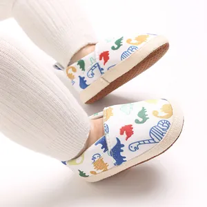 Primer plano de zapatos blancos para bebés con estampados de dinosaurios de colores y suela