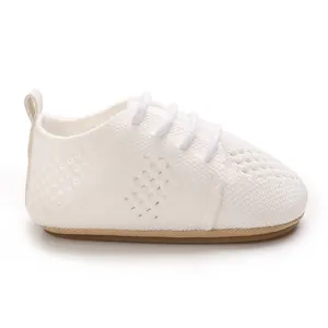 Close-up of white knitted baby princess shoes with breathable hollow design and laces.