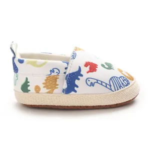 Vista lateral de zapato de lona blanca para bebé con estampados de dinosaurios de colores