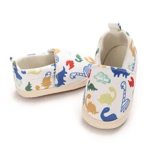 Primer plano detallado de zapatos de bebé blancos con divertidos estampados de dinosaurios.