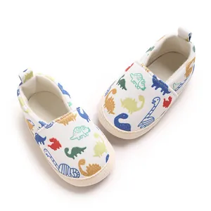 Vista superior de zapatos de lona para bebé con estampado de dinosaurios y suela blanda.