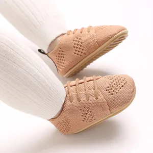 Detailed macro shot of beige knit infant flat shoes featuring hollow-out patterns and laces