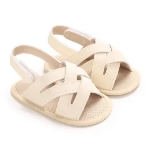 Detalle de sandalias de bebé en PU crema con diseño de correas cruzadas y suela blanda