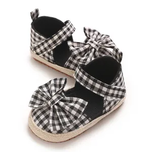 Detailansicht von schwarz-weißen Gingham-Babysandalen mit einer dekorativen Schleife