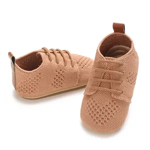 Close-up detail of the hollow heart pattern on these retro knitted infant flat shoes in camel