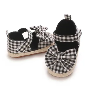 Detailansicht von schwarz-weißen Gingham-Babysandalen mit Schleifen und Jutepreism