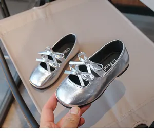 Close-up of stylish silver girl's flat shoes featuring an elegant bow detail