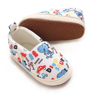 Vista detallada de zapatos blancos para bebés con estampados de dinosaurios y coches
