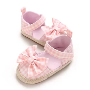 Nahaufnahme der rosa-weiß karierten Babysandalen mit einer großen Zierschleife.