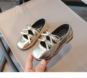 Close-up of girl's gold square-toe dress shoes with bow detail and shiny finish