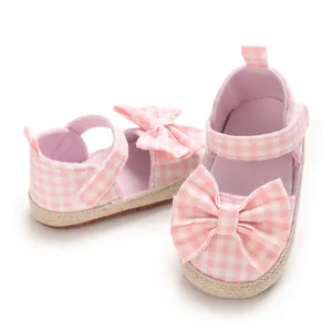 Nahaufnahme rosa karierter Babysandalen für Mädchen mit Schleifen und Seilsohlendetails