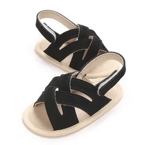 Detalle de sandalias de bebé para caminar con tiras cruzadas negras y suela blanda