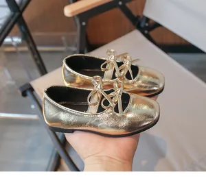 Close-up detail of gold metallic girl's Mary Jane shoes with elegant double bow knots