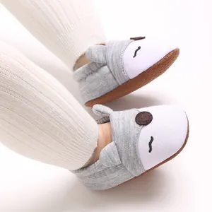 Dettaglio di scarpe morbide per neonati grigie e bianche con design a faccia di animale