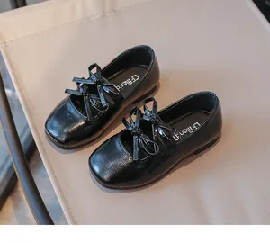 Detail view of girls' black patent leather shoes featuring stylish double bow accents