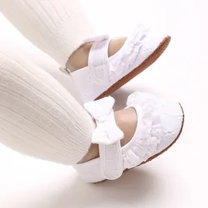 Vista dettagliata di scarpe piatte bianche da principessa per neonata con volant e fiocco