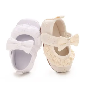 Dettaglio scarpe da principessa per neonata con volant in pizzo e fiocco decorativo