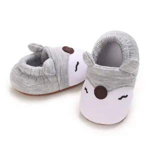Dettaglio di scarpine morbide per neonati con viso di animale in grigio e bianco