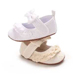 Dettaglio di scarpe da principessa per neonata con graziosi volant e ricami floreali