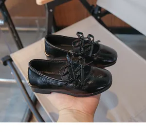 Detailed view of shiny black patent leather girls' shoes featuring a cute bow decoration.