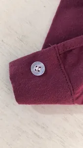 Detailed macro view of the white button and fabric texture on a wine red cotton linen shirt