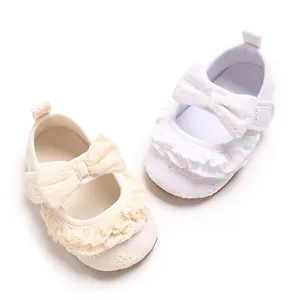 Dettaglio scarpe da principessa per neonata bianche e crema con volant e fiocchi decorativi