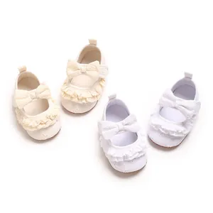 Dettaglio di scarpe da principessa per neonata bianche e crema con volant e fiocchi