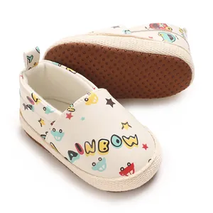 Primer plano de zapatos de bebé blancos con texto de arcoíris y estampados de coches