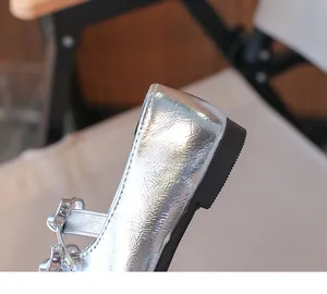 Macro detail of silver metallic finish on children's bow-accented leather flat shoes
