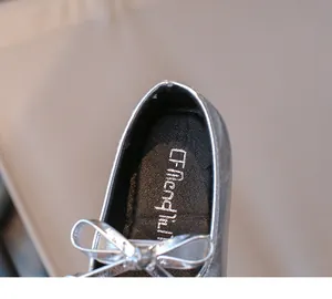 Close-up of silver girls loafer shoe featuring metallic finish and bow detail