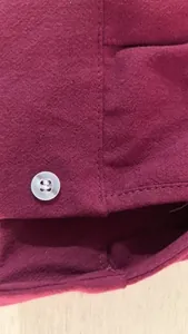 Close-up detail of a men's burgundy linen shirt showing fine fabric texture and button.