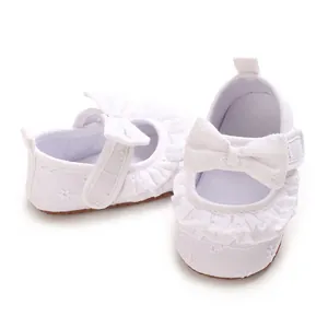 Dettaglio delle scarpe da principessa bianche per neonata con volant in pizzo e fiocco
