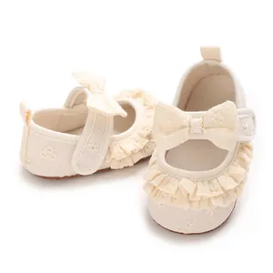 Primo piano scarpe neonata panna con eleganti volant, fiocco e ricami floreali delicati