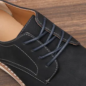 Primer plano de zapato casual de cuero negro con cordones azules y costuras blancas