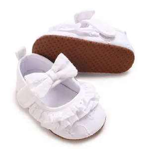 Dettaglio scarpe neonata bianche con volant ricamati e fiocco elegante