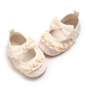 Dettaglio scarpe da principessa per neonata con pizzo color crema e fiocco decorativo