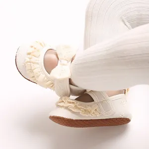 Primo piano di sandali bianchi da neonata con volant e dettaglio fiocco decorativo