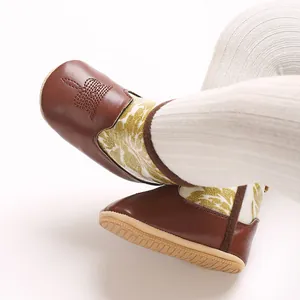 Close-up of baby leather boots with soft anti-slip soles and gold floral pattern.
