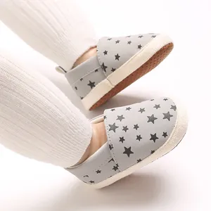 Dettaglio scarpe neonato grigie con stampe di stelle nere e suole morbide antiscivolo