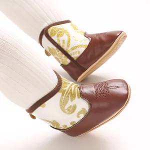 Close-up of baby winter boots with gold glitter pattern and brown embroidered toe cap