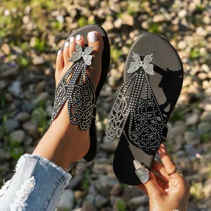 Detalle de sandalias negras con alas de mariposa de diamantes de imitación brillantes para mujer