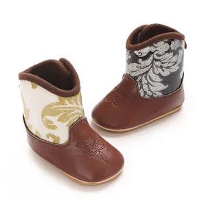 Detail of baby winter boots with elegant gold and silver leaf patterns on PU leather.