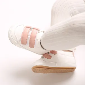 Nahaufnahme von weißen Baby-Lernlaufschuhen aus PU-Leder mit rosa Klettverschlüssen