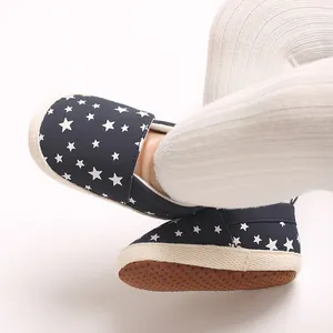 Dettaglio scarpe neonato blu scuro con stelle, suole morbide antiscivolo e leggings bianchi