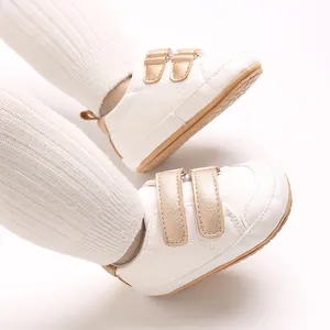 Detailansicht von weißen Babylauflernschuhen mit goldenen Klettverschlüssen und Sohle.